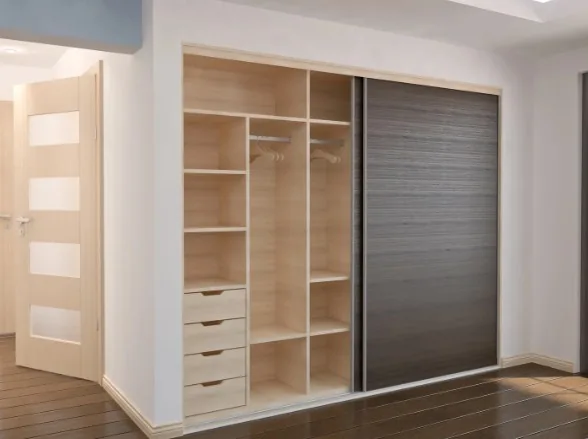 Interior de armario empotrado en madera clara con baldas, barra de colgar y cajones, puerta corredera oscura, en Miranda de Ebro