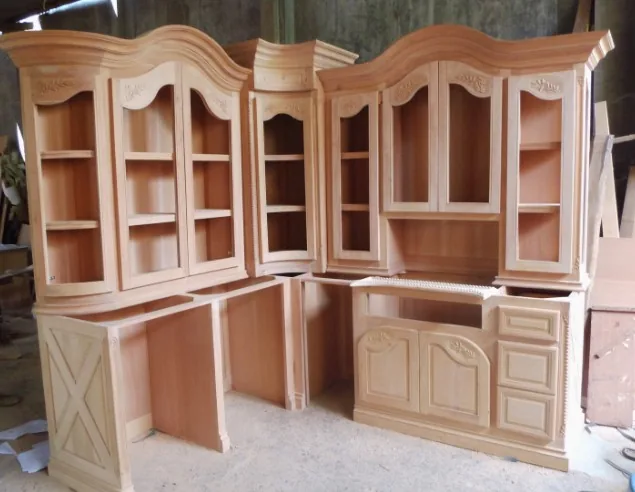 Mueble de cocina en madera cruda sin barnizar con vitrinas y molduras clásicas, fase de fabricación en taller en Burgos