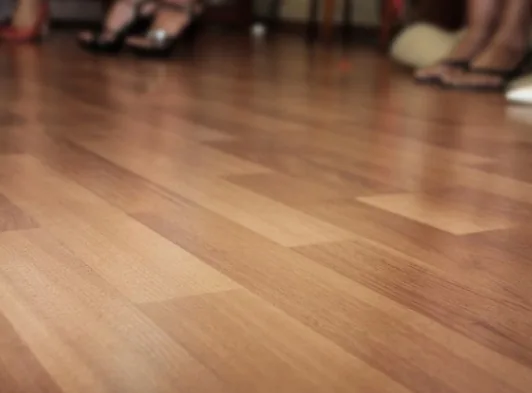 Primer plano de suelo de madera clara recién barnizado tras sustituir lamas astilladas en Burgos