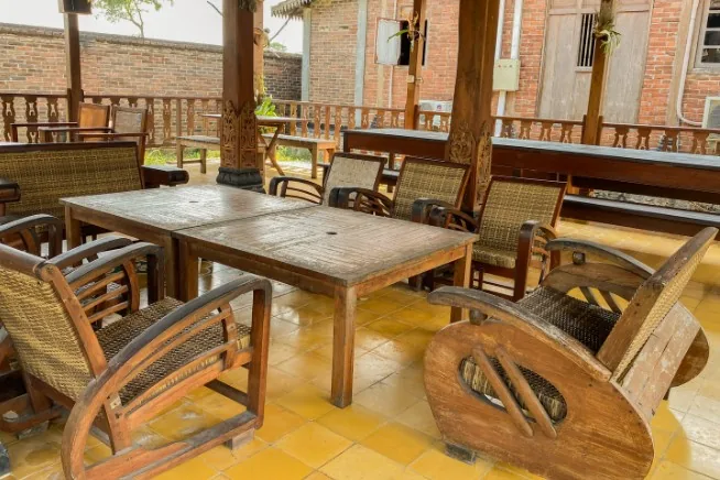Conjunto de mesa y sillones de ratán y madera oscura en porche cubierto de estilo rústico en Burgos
