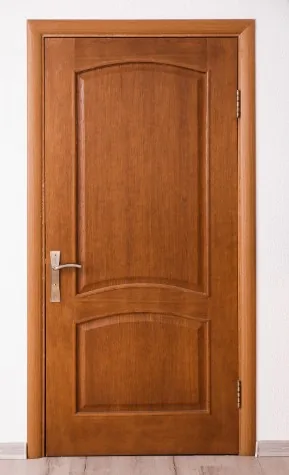 Puerta interior de madera de roble con paneles curvos y manilla plateada en Burgos